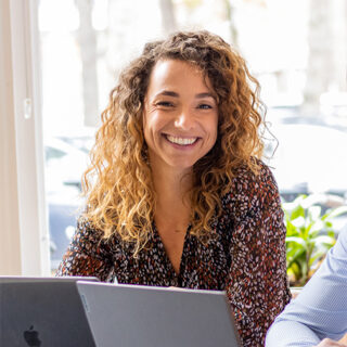 Vrouw poseert lachend achter laptop