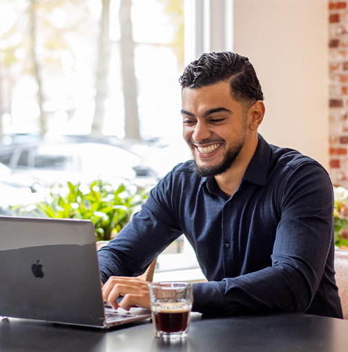Man zit lachend achter laptop